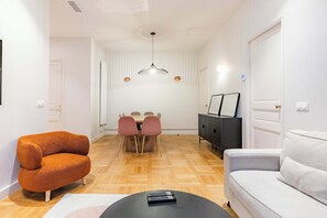 A modern living room with a sofa, a coffee table, and a dining area with a table and chairs. - Charming - Air-conditioned and Terrace (Paris)