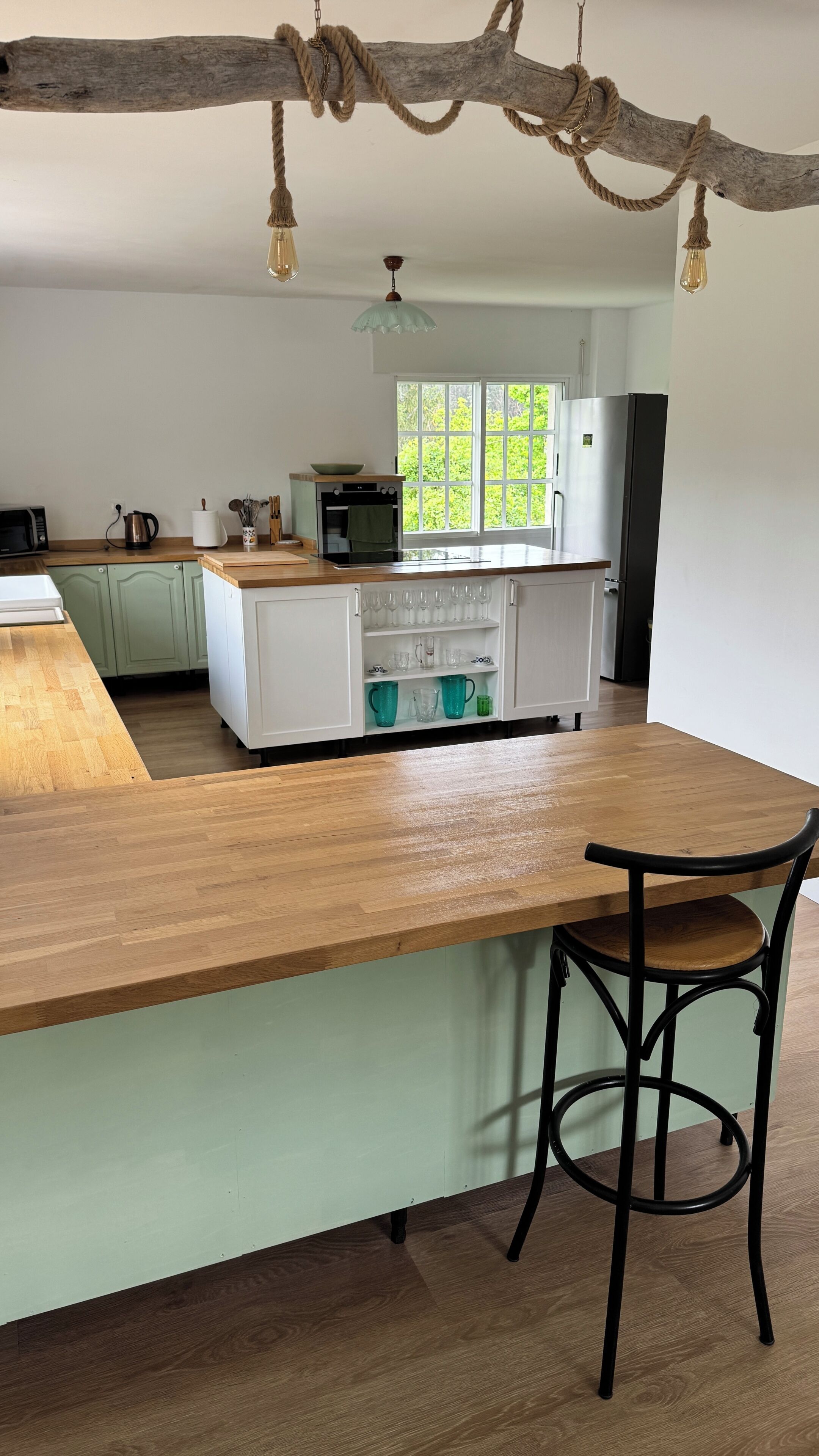 A modern kitchen with a wooden island, a built-in oven, and a refrigerator.