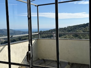 Un balcon doté d’une rambarde en métal, d’où l’on peut admirer un paysage montagneux.