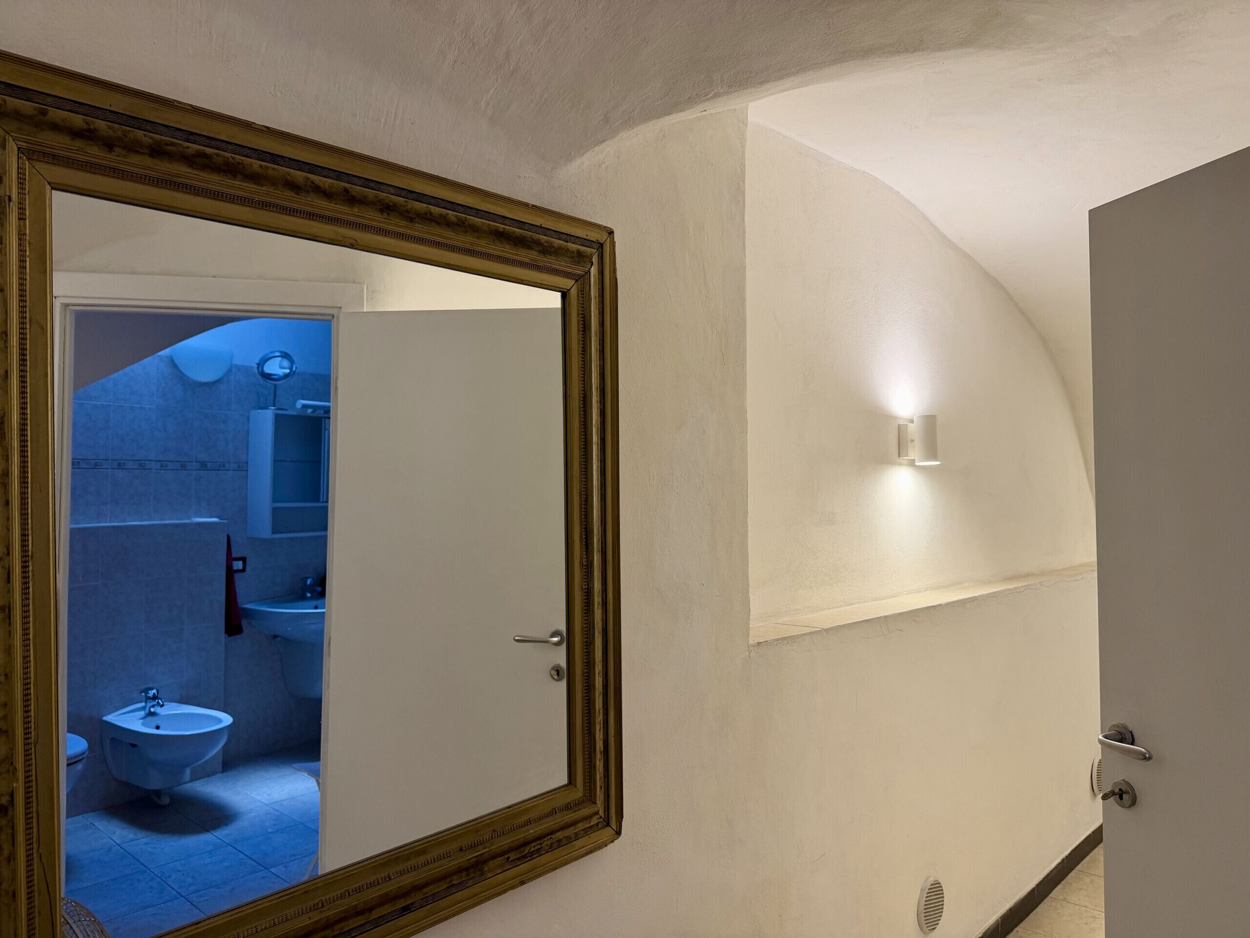 A bathroom with a mirror, sink, and toilet.