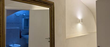 A bathroom with a mirror, sink, and toilet.