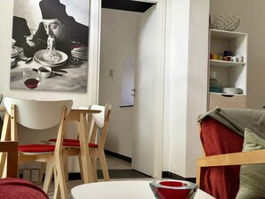 A dining area with a table, chairs, a painting, and a shelf with dishes. - Casa Don Camillo (Dolcedo)