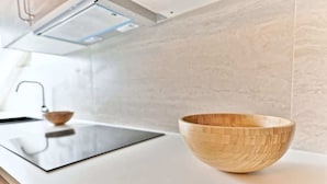 Une cuisine moderne avec un saladier en bois posé sur le plan de travail, un évier et un pare-éclaboussures.
