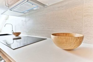 A modern kitchen with a wooden bowl on the counter, a sink, and a backsplash. - Design & bright apartment, Victor Hugo (Paris)