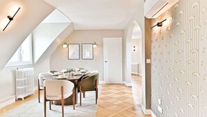 Un espace repas moderne avec une table en bois, des chaises blanches et des tableaux encadrés accrochés au mur.