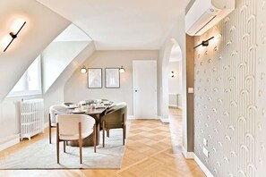 A modern dining area with a wooden table, white chairs, and framed pictures on the wall. - Design & bright apartment, Victor Hugo (Paris)