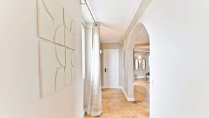 Un couloir avec un plancher en bois, des murs blancs et une porte au fond.