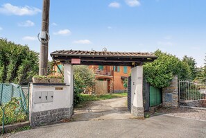 Ein begrenzter Eingangsbereich mit einer Pergola, einem Strommast und einem Gebäude mit Ziegeldach.