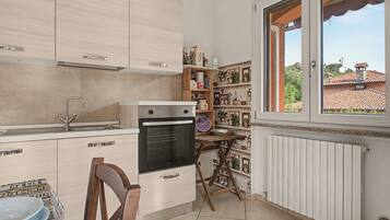 A compact kitchen with a built-in oven, a sink, and a window overlooking a residential area.