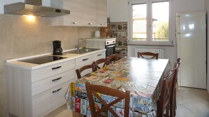 Een keuken met een eettafel bezaaid met nummerplaten, een koffiezetapparaat en een koelkast.