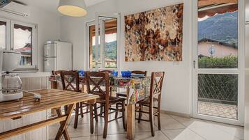 Un coin repas avec une table et des chaises, un réfrigérateur, un tableau représentant une zèbre accroché au mur, et une vue sur l’extérieur grâce à une porte vitrée.
