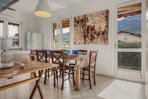 A dining area with a table and chairs, a refrigerator, a wall-mounted zebra painting, and a view of the outdoors through a glass door.