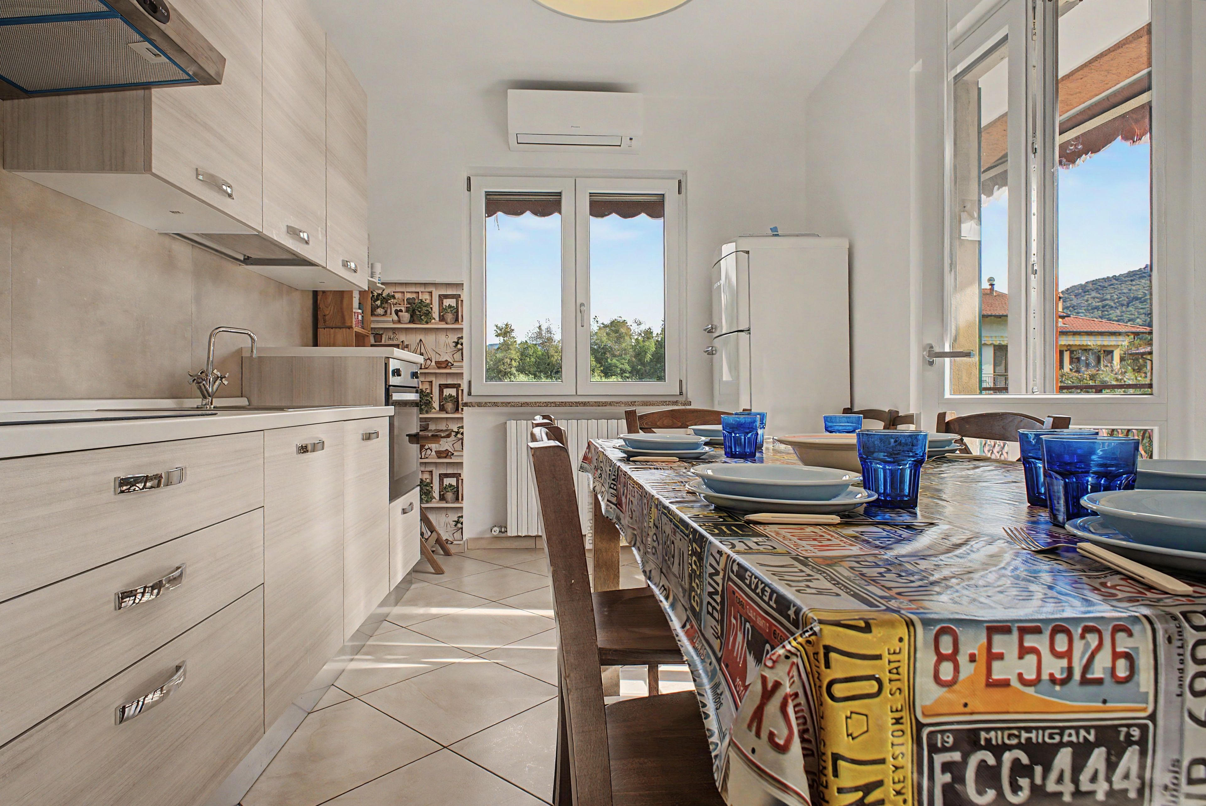 Una cucina moderna con zona pranzo, con isola centrale, frigorifero e finestra vista all'esterno.