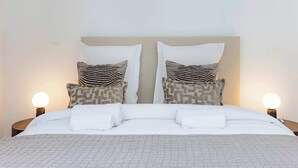 A neatly made bed with white linens and two pillows with a striped pattern. - Appartement de prestige climatisé (Paris)