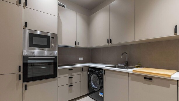 A compact kitchen with a built-in microwave, oven, and dishwasher. - Appartement de prestige climatisé (Paris)