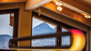 Une fenêtre donnant sur une montagne et une zone boisée.