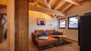 Un salon chaleureux avec un plafond en bois, un canapé en cuir marron et une petite table sur laquelle se trouve une lampe.