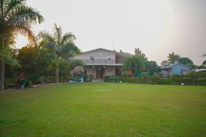 A house with a front lawn, a decorative garden feature, and a clear sky. - Taj Royal Farm (Noida)