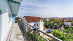 Een balkon met uitzicht op een woonwijk, met huizen met rode pannendaken en een heldere lucht.