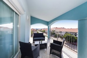 Ein Balkon mit einer Couch, zwei Stühlen und einem kleinen Tisch.