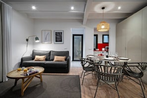 Ein modernes Wohnzimmer mit Sofa, Couchtisch und Essbereich mit Stühlen und Tisch.