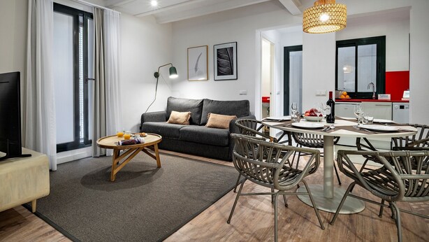 Ett modernt vardagsrum med en soffa, ett matbord, stolar och en tv.
