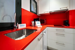 A modern kitchen with red countertops, stainless steel appliances, and white cabinetry. - Rustic-Chic Gracia Apartment Verdi Bajos (Barcelona)