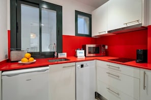 Eine kleine Küche mit roter Arbeitsplatte, einer Mikrowelle, einem Toaster und einem Spülbecken.