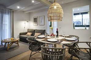 Ein modernes Wohnzimmer mit einem runden Esstisch für zwei Personen, einer Couch und einer Pendelleuchte.