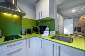 Eine moderne Küche mit einer grünen Arbeitsplatte, Edelstahlgeräten und weißen Schränken.