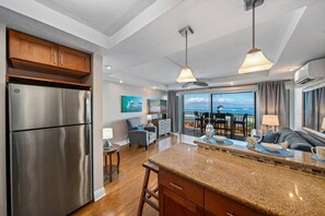 Eine moderne Küche mit einem Edelstahl-Kühlschrank, Granit-Arbeitsplatten und einem Essbereich mit Meerblick.