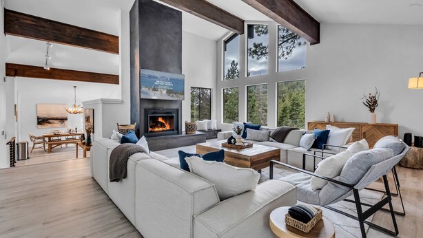 A spacious living room with a fireplace, large windows, and a high ceiling with exposed beams. - Tahoe Retreat | Private Hot Tub & Scenic Views (Incline Village)