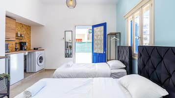 Habitación de hotel moderna con dos camas, kitchenette, lavadora y vistas al exterior.