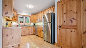 A kitchen with wooden cabinets, a stainless steel refrigerator, and a window with an 'EXIT' sign.