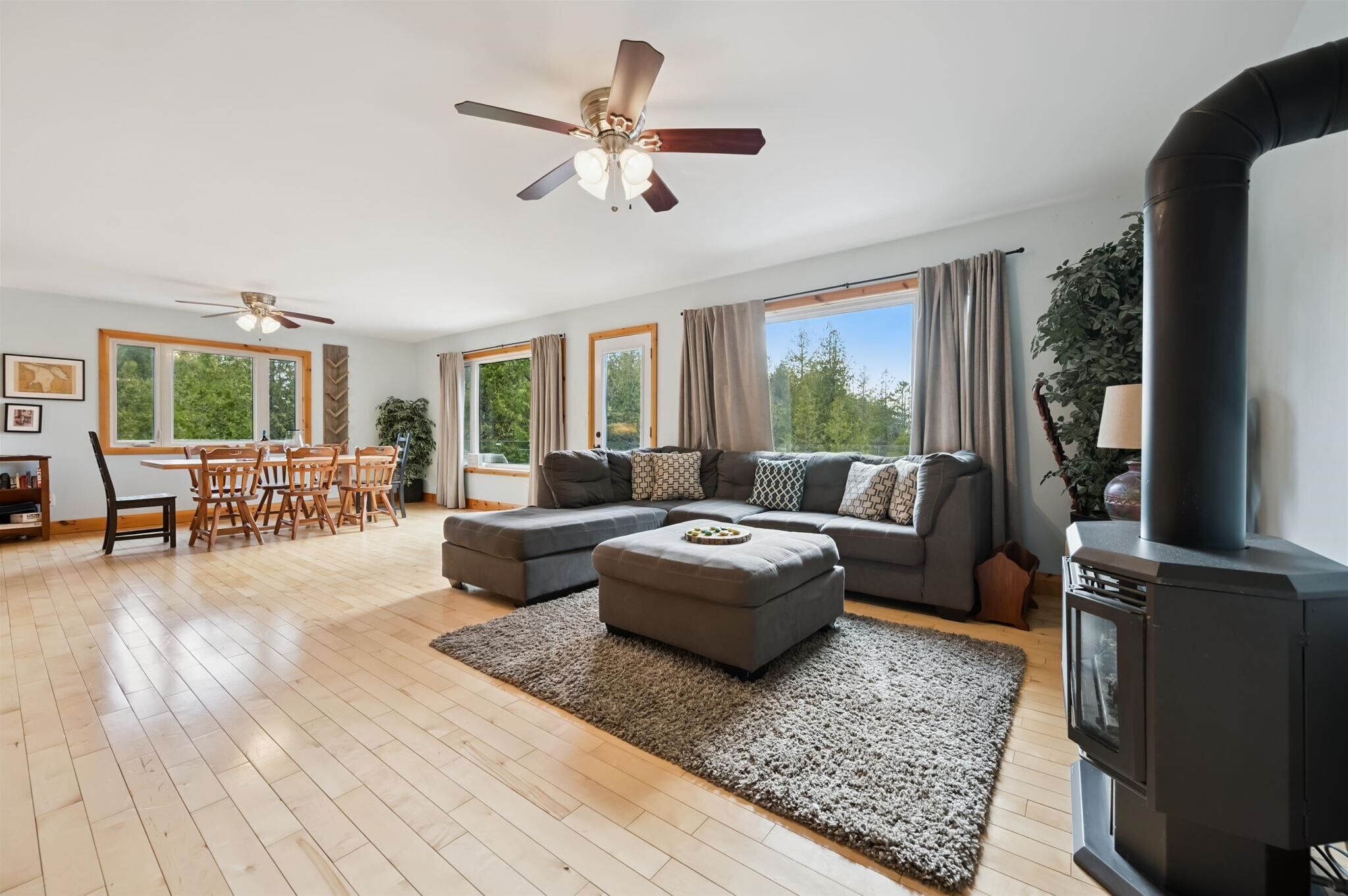 A spacious living room with a large sofa, a dining table with chairs, a ceiling fan, and a fireplace.