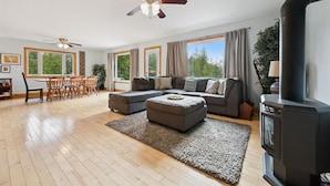 A spacious living room with a large sofa, a dining table with chairs, a ceiling fan, and a fireplace.