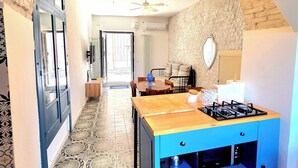 A kitchen with a blue island, a ceiling fan, and a patterned floor.