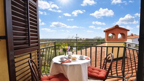 Een balkon met een tafel gedekt voor twee personen, een stoel en uitzicht op het landschap.