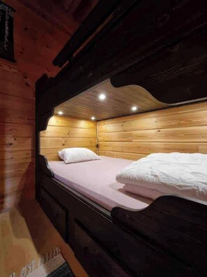 A bunk bed room with wooden walls and a sloped ceiling.