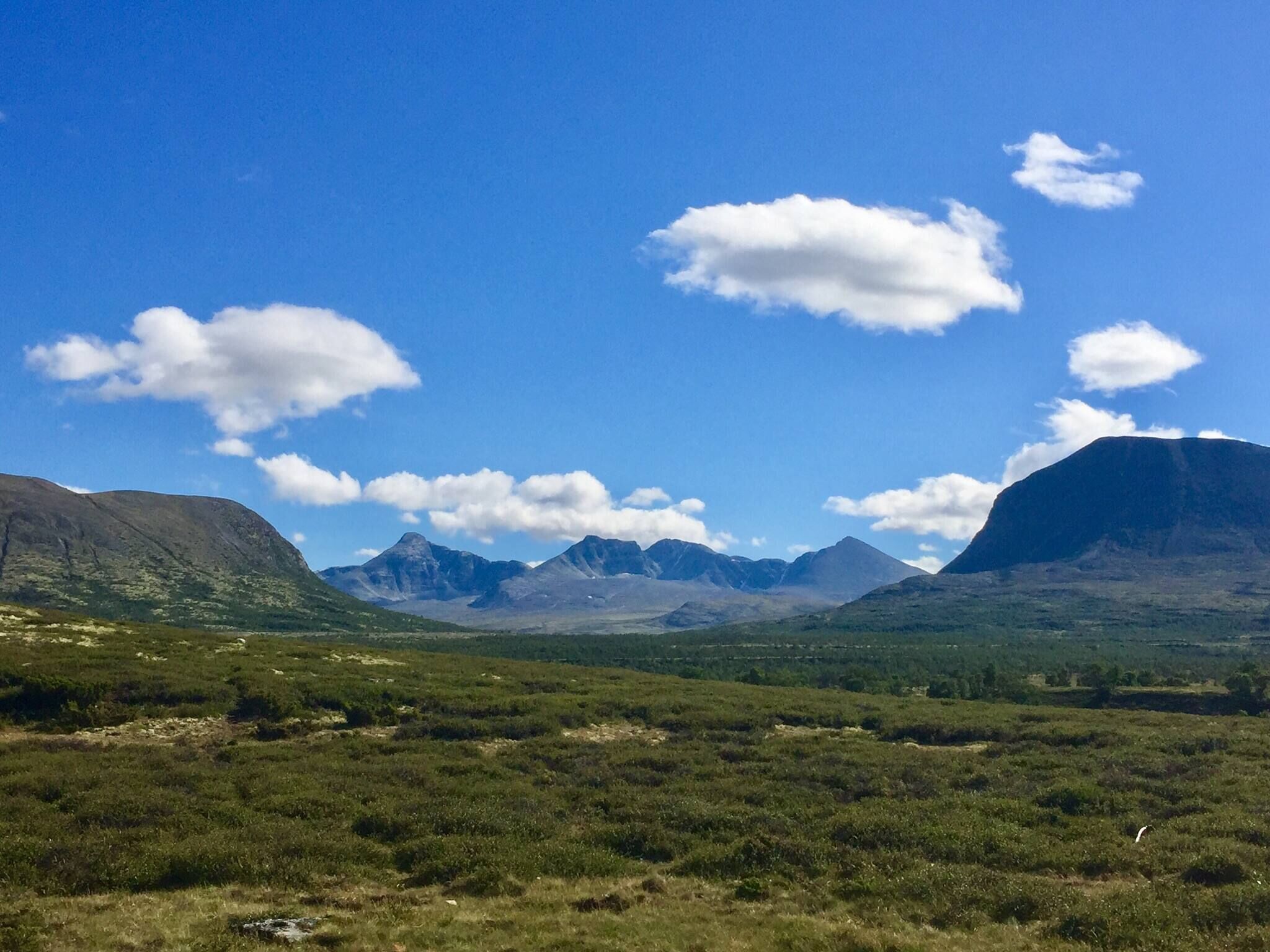 A mountainous landscape with a clear sky and scattered clouds.