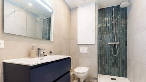 Un baño moderno con un espejo grande, un lavabo, un inodoro y una ducha.