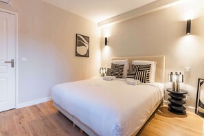 A hotel room with a large bed, a bedside table, a wall-mounted light, and a framed picture. - Escapade Climatisée Marais : Le Chic Parisien (Paris)