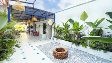 A hotel lobby with a tiled floor, a brick planter, and various plants.