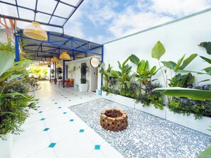 Vestíbulo de hotel con piso de baldosas, una jardinera de ladrillo y diversas plantas.