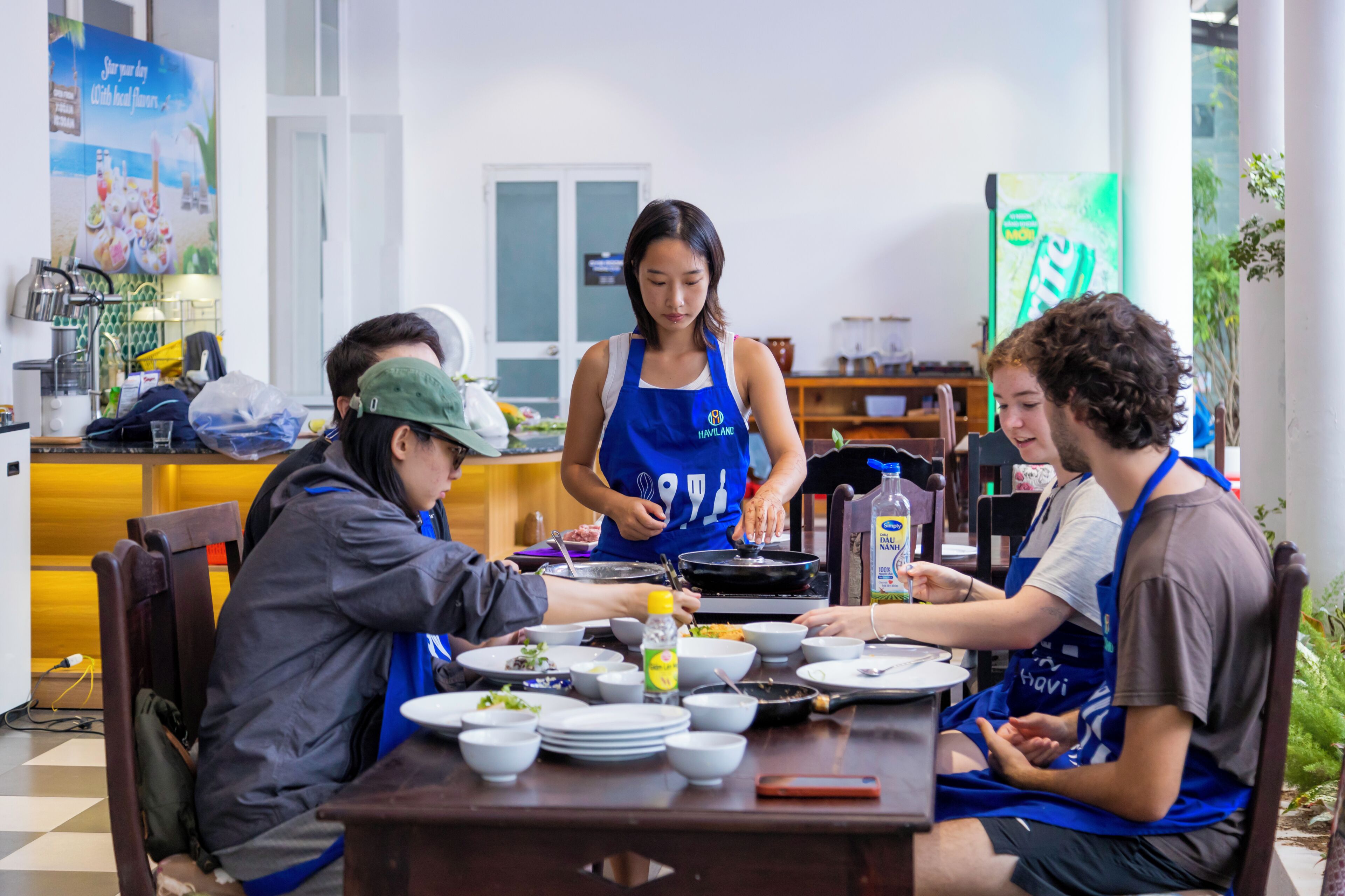 A group of people dining at a table with a chef serving food.