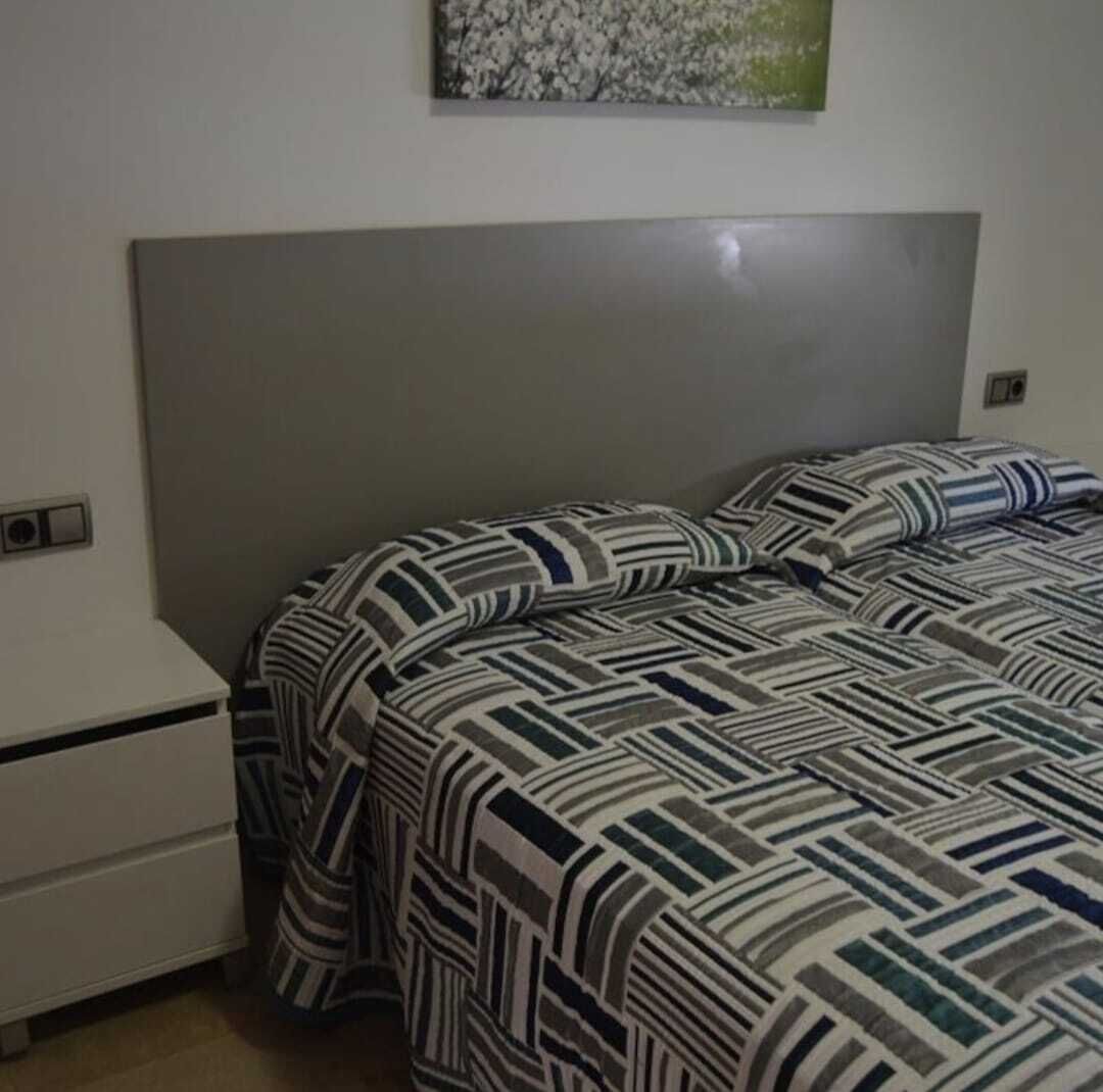 A bedroom with a bed, a nightstand, and a wall-mounted light switch.