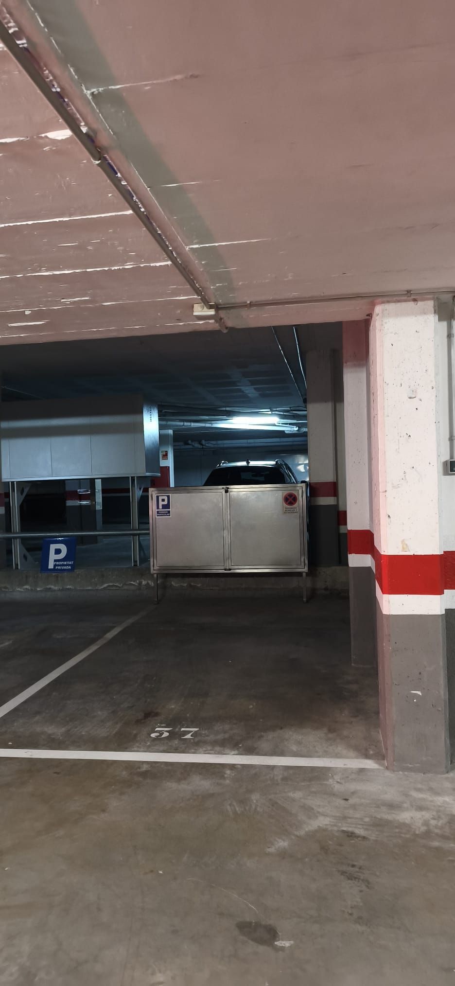 Eine Tiefgarage mit Metallgitter, einem Parkplatzschild mit 'P' und einem Schild mit der Aufschrift 'PRIVATE'.