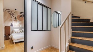 A modern interior with a staircase, a bed, and a wall-mounted mirror. - Triplex d'exception 150m2 - 6BR (Paris)
