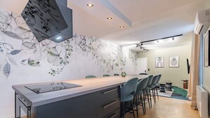 A modern kitchen with a central island, dark cabinetry, and a floral wall mural. - Triplex d'exception 150m2 - 6BR (Paris)