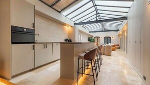 A modern kitchen with a central island, bar stools, and a skylight. - Splendeur de 187m² Climatisé au Cœur de Paris (Paris)